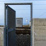 Sulla sinistra il muretto � interrotto da una porta in metallo che permette di attraversare i binari